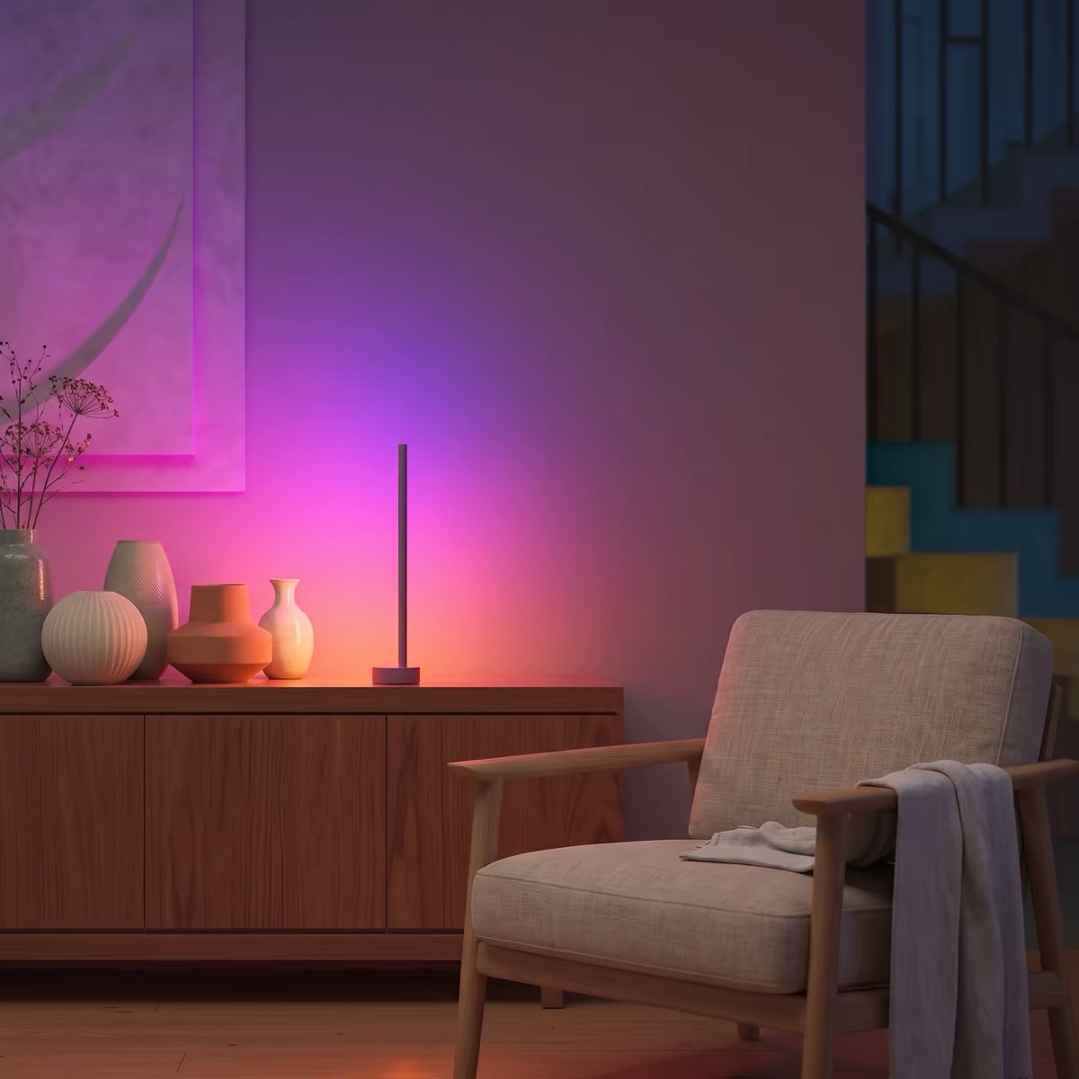 A small table lamp casting pink and amber beside an armchair