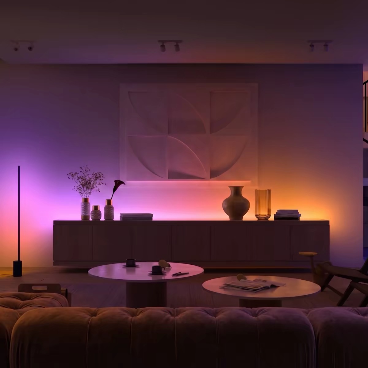 A living room framed by a floor lamp and pink-amber cabinet lighting